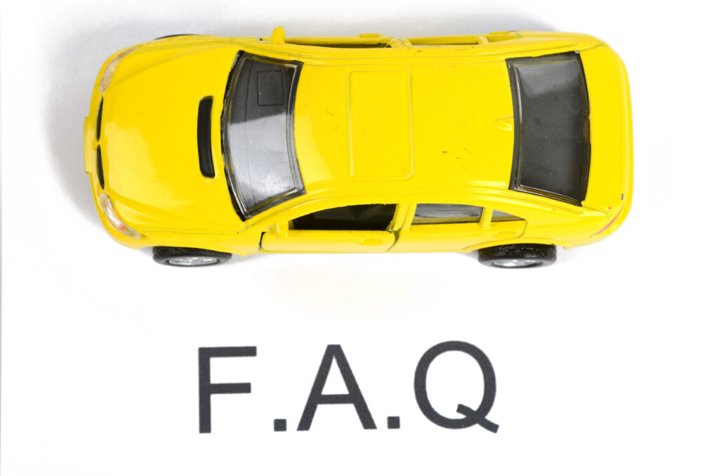A yellow toy car is positioned above the bold letters "F.A.Q" on a white background, as seen from a top-down view.