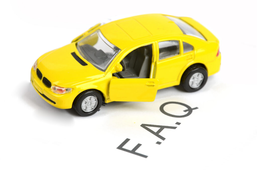 A yellow toy car with its front door open is placed on a white surface above the letters "F.A.Q.